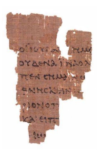 A small, roughly triangular scrap of brown papyrus with seven partial lines of Greek capital letters written in black ink