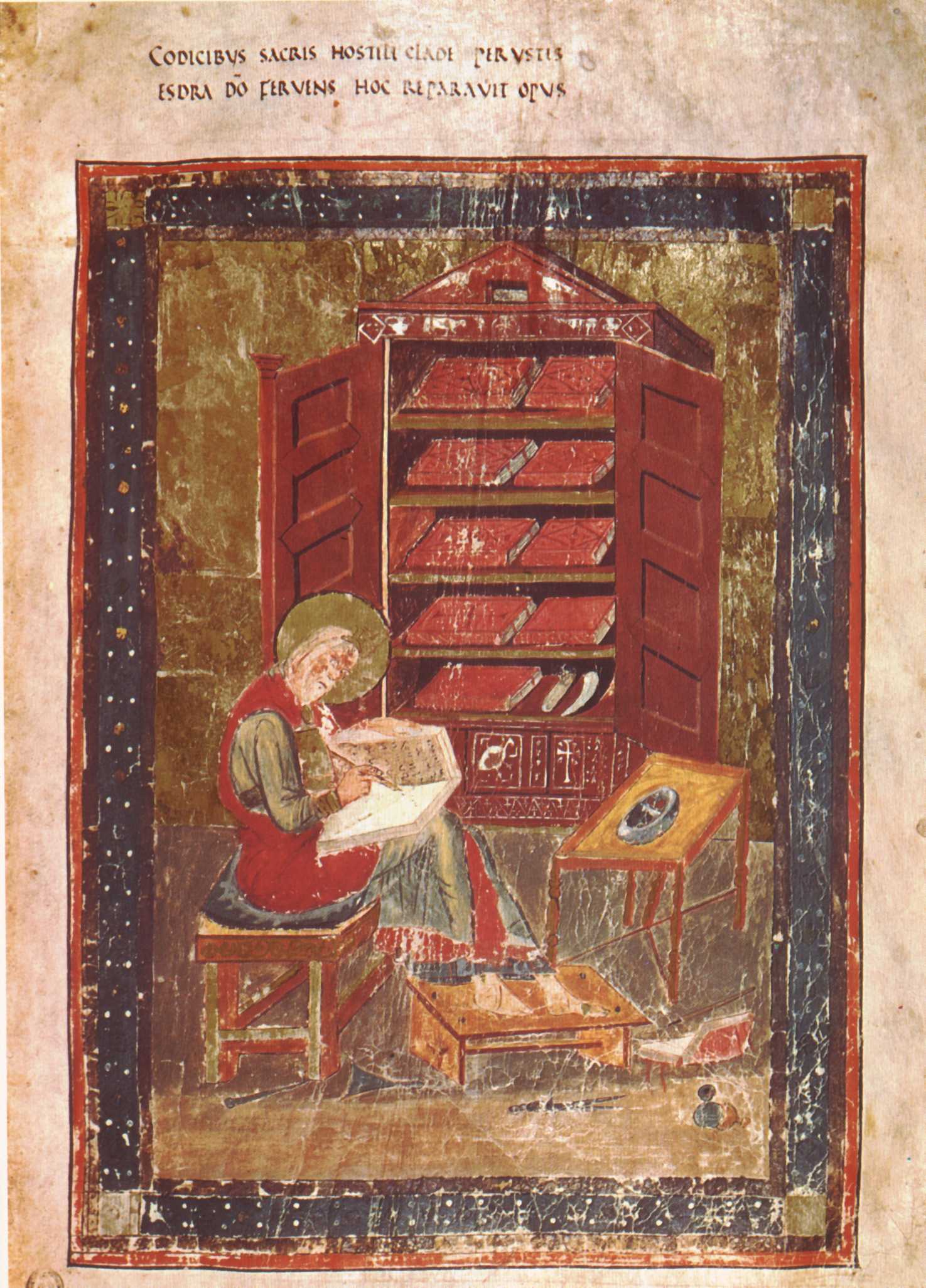 Painted manuscript page showing a bearded, haloed scribe seated on a bench, writing in a book on his knee, in front of an open cupboard filled with books; a Latin inscription runs across the top