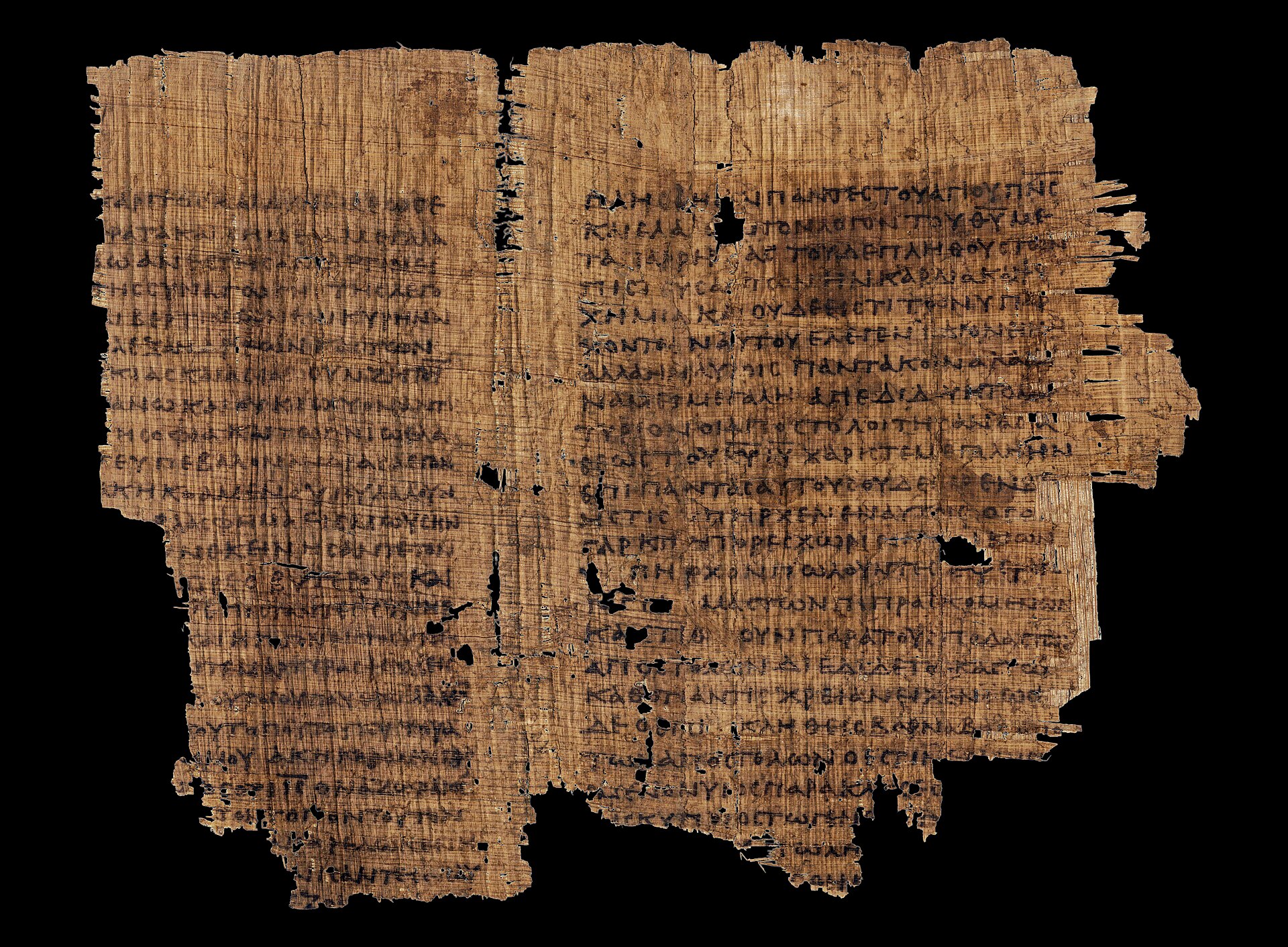 A brown papyrus fragment with lines of Greek capital letters, torn at the edges