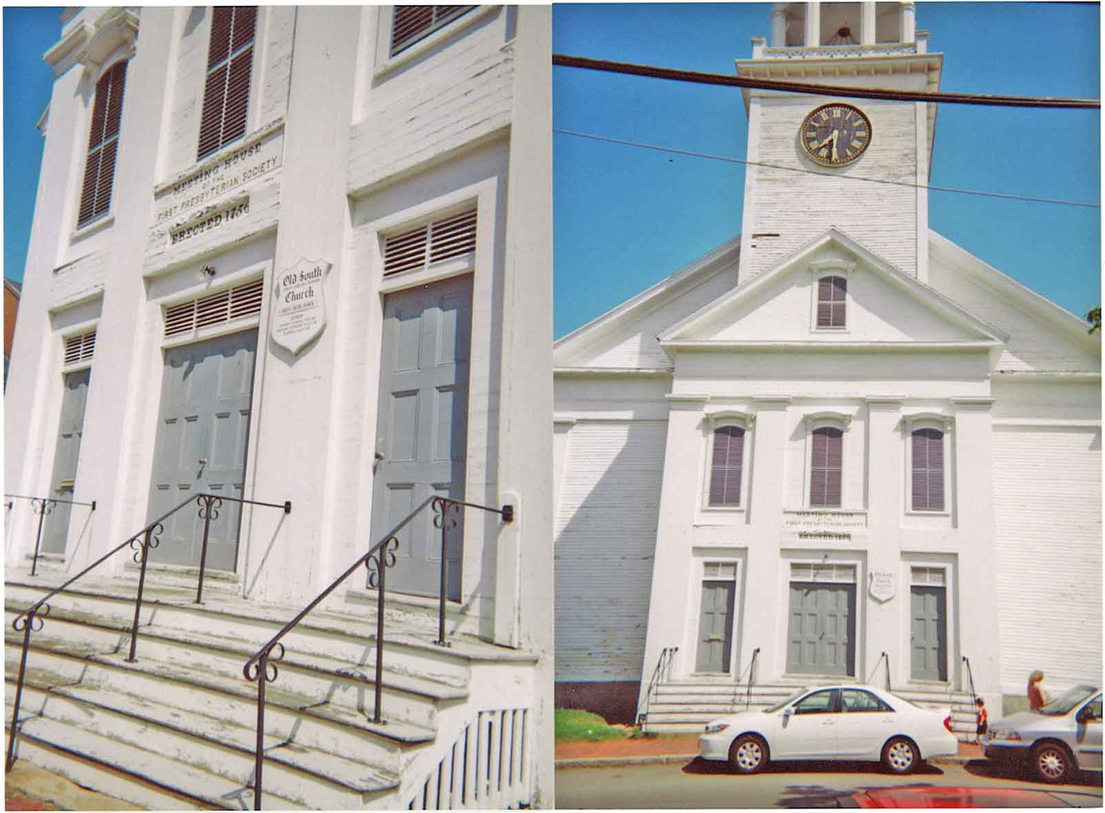 White wooden church with a tall multi-stage steeple and clock, set behind a fence on a tree-lined street