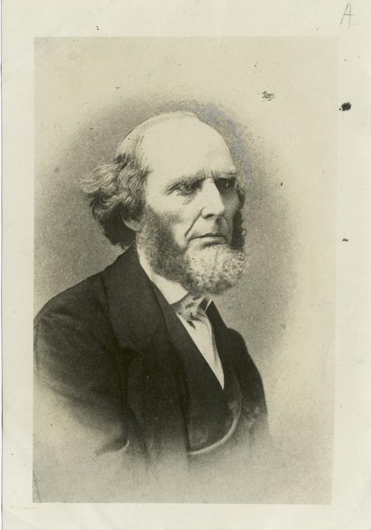 Head and shoulders portrait of an older man with thinning white hair, deep-set eyes and a stern expression, wearing a dark coat and white collar