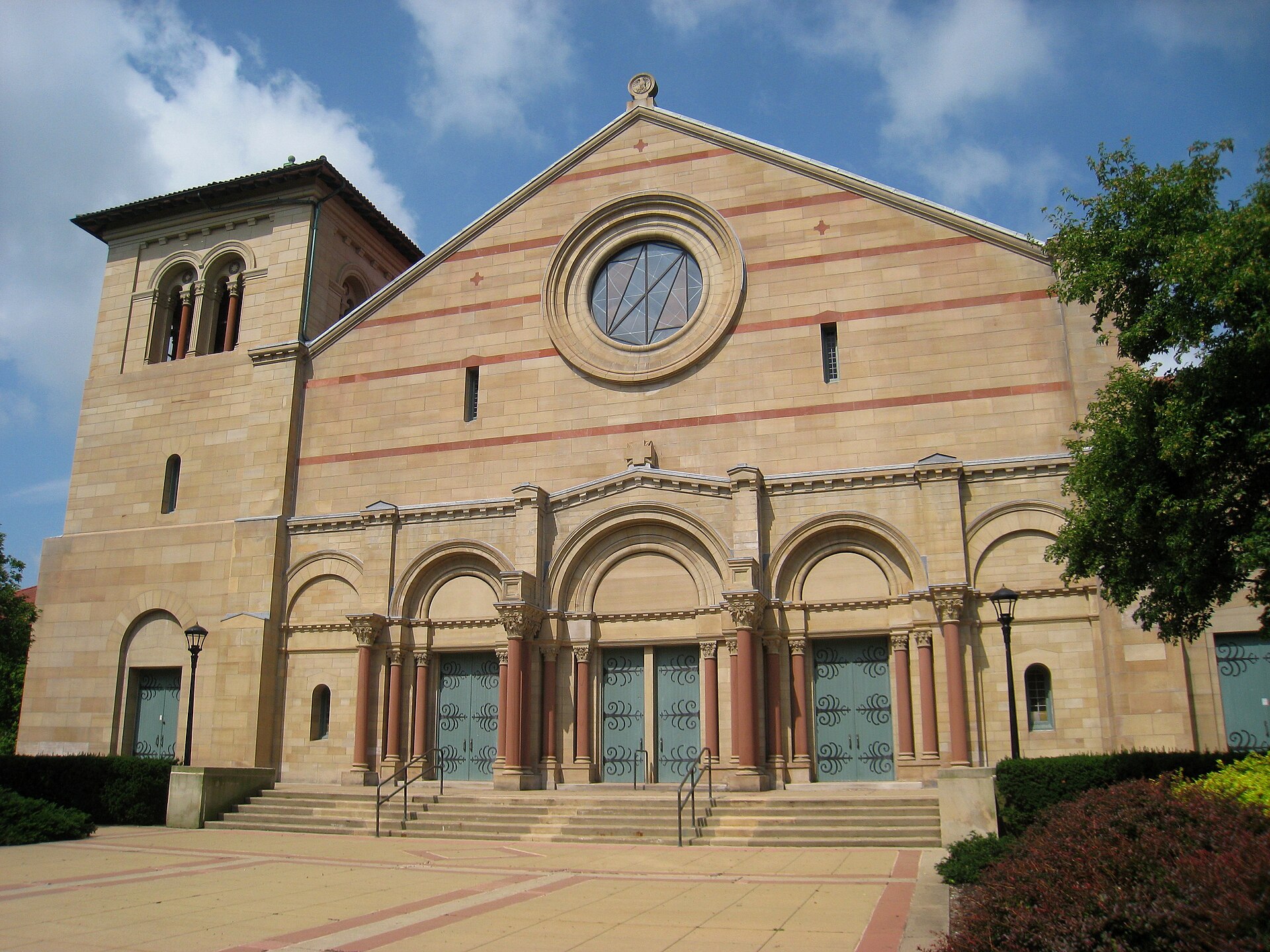 Large stone chapel with broad arched openings across its front and a tiled roof, seen from the front