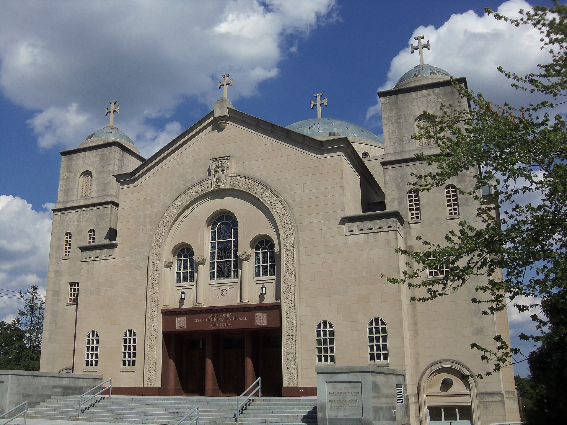 Exterior of a large Byzantine style cathedral with a broad central dome, round arched windows and a wide stone stairway, in Washington, D.C.