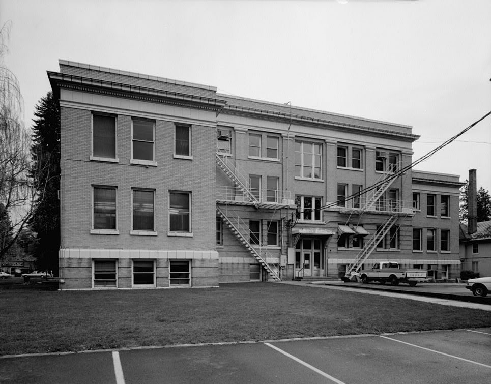 Black-and-white photo of the back of a three-story brick courthouse with metal fire escapes