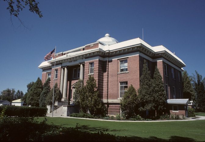 Two-story stone county courthouse with arched windows on a corner lot, St. Anthony, Idaho