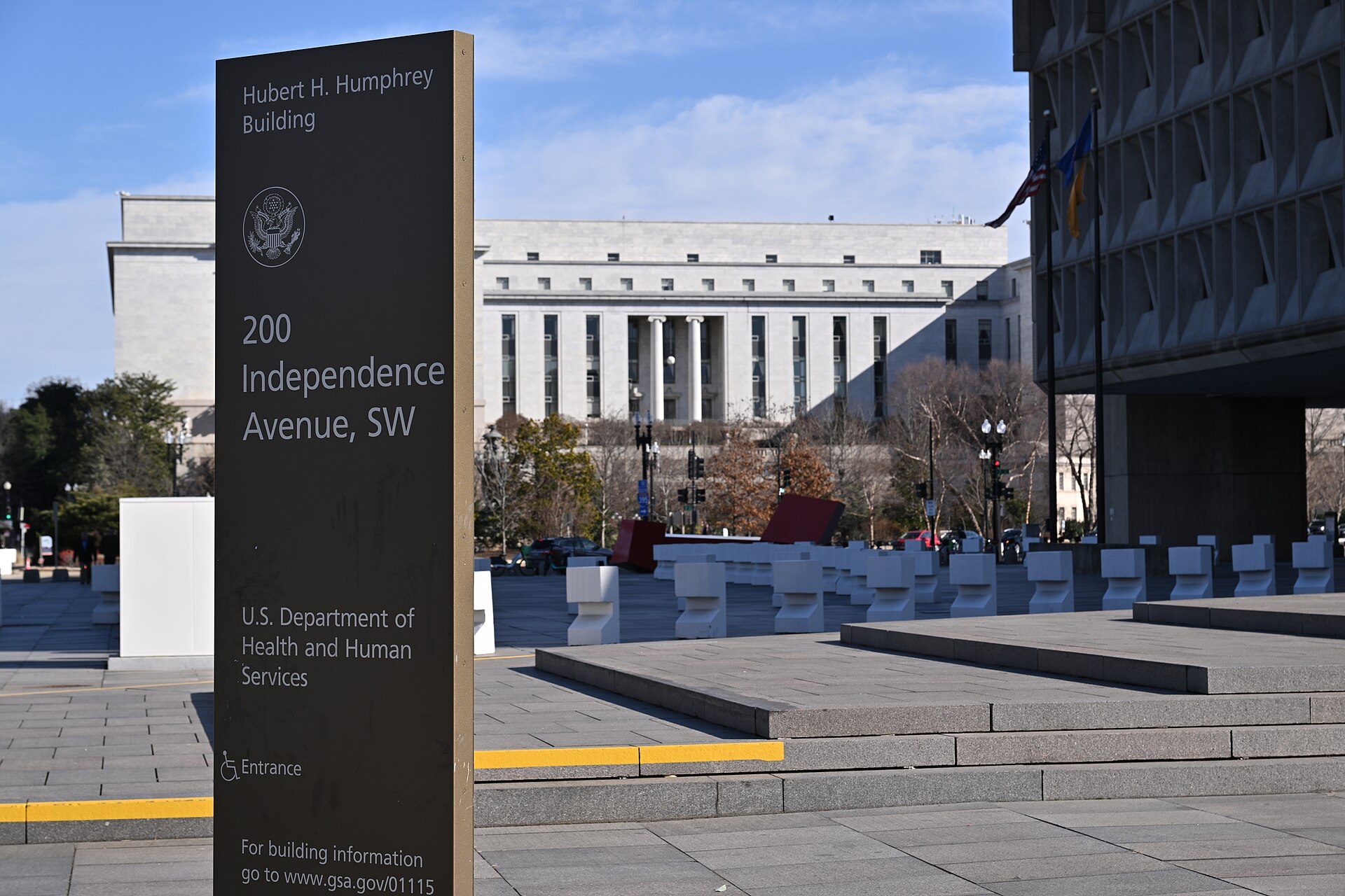A low stone sign reading Department of Health and Human Services in front of a large building on a clear day in Washington, D.C.