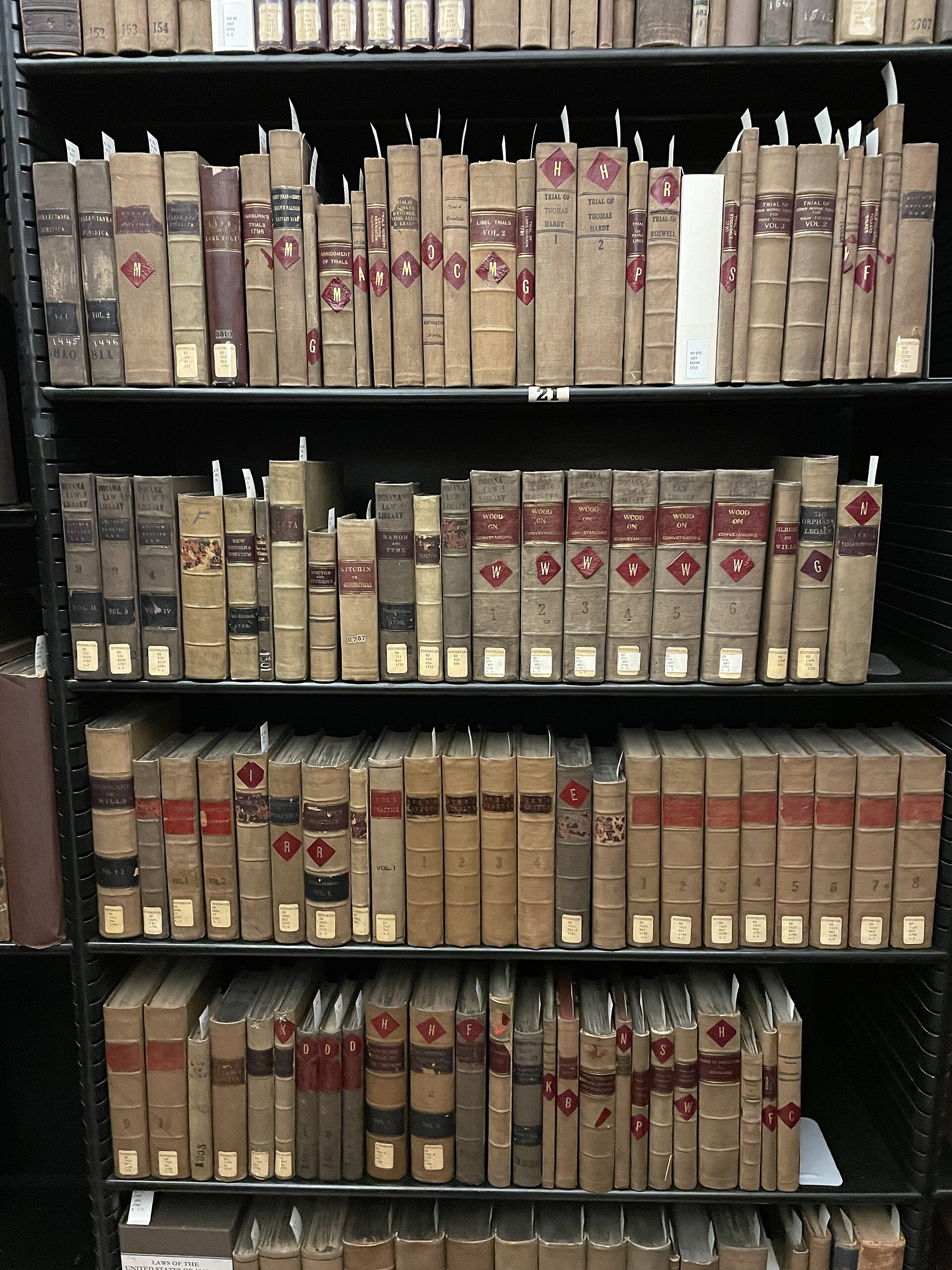 A wooden shelf of old leather-bound law books with worn spines and faded gold lettering in a court law library.