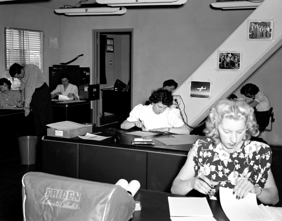Women at desks working with calculators and data sheets in the NACA computer room, 1949