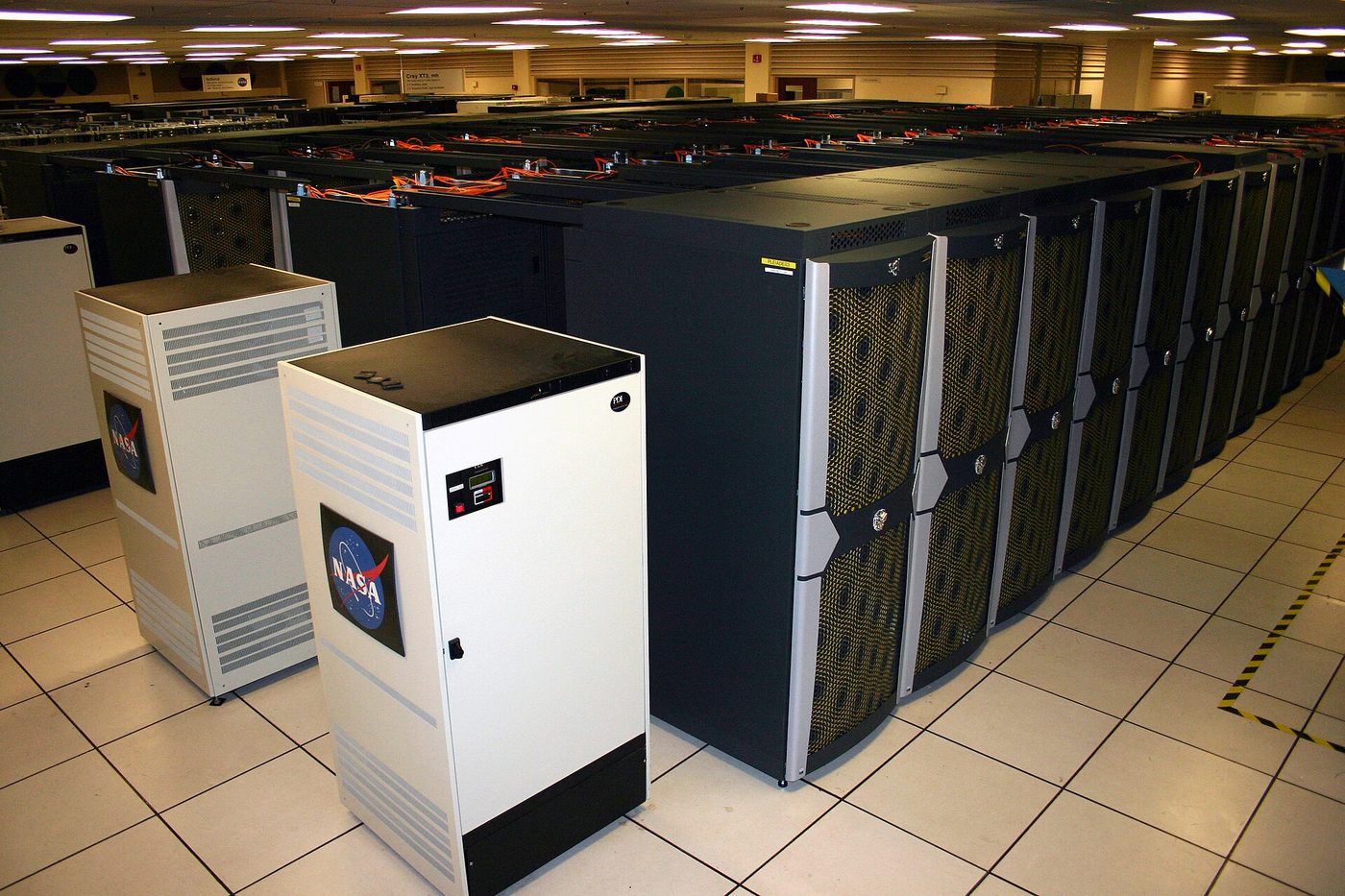 Long rows of black computer cabinets in a large, brightly lit machine room