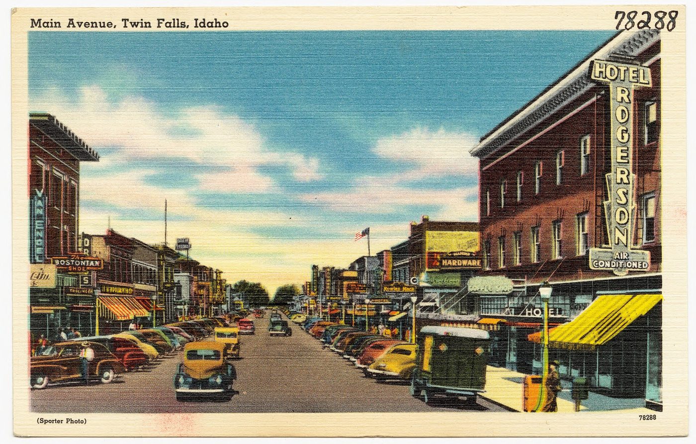 Color postcard of Main Avenue in downtown Twin Falls, Idaho, with brick storefronts, parked cars and a wide street