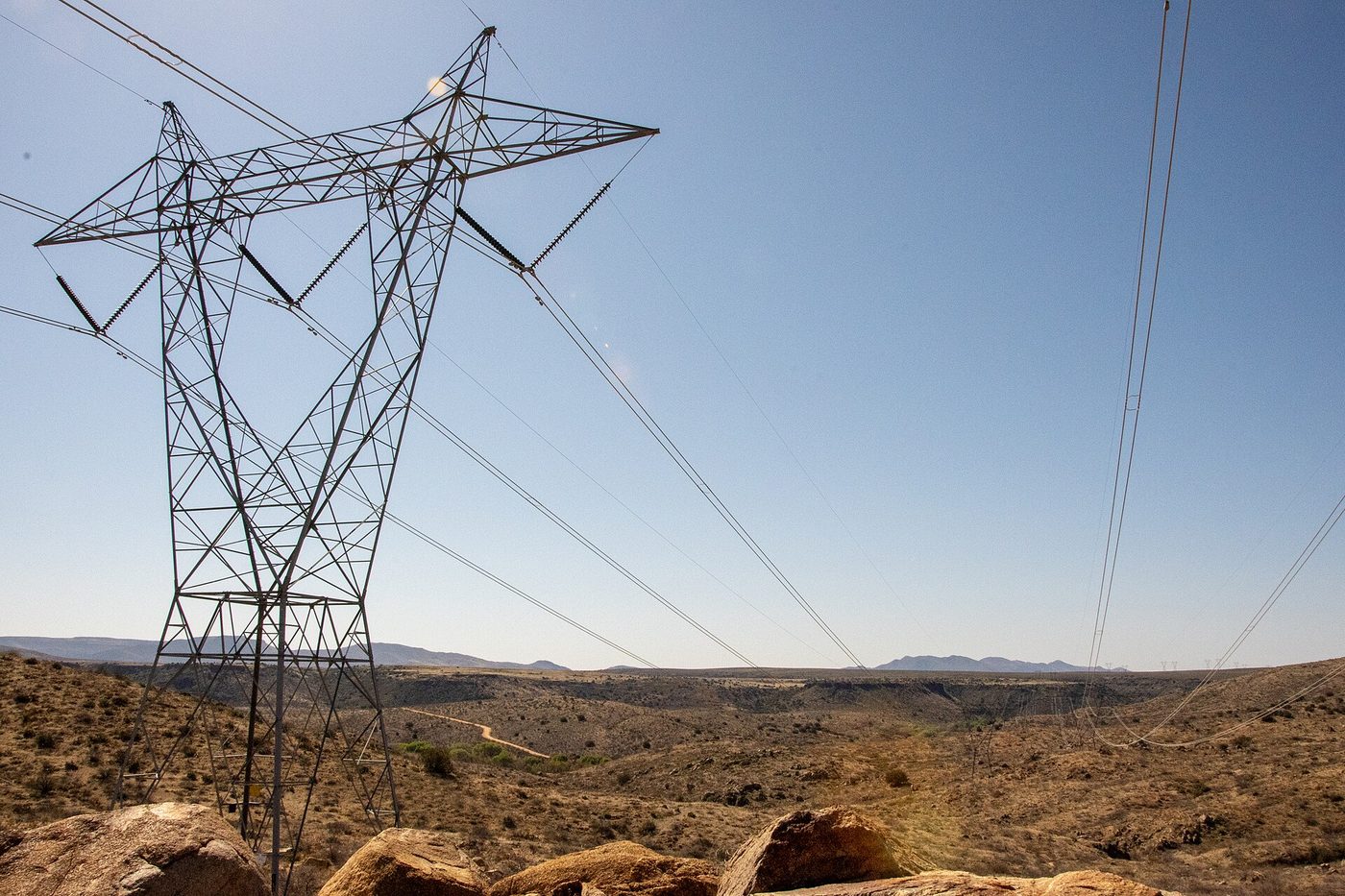 High-voltage transmission towers and lines crossing open desert public land under a wide sky