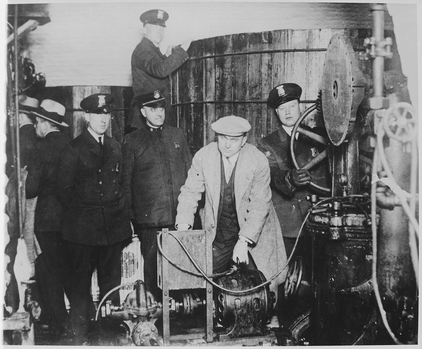 Detroit police officers standing among barrels, vats and equipment in a hidden underground brewery