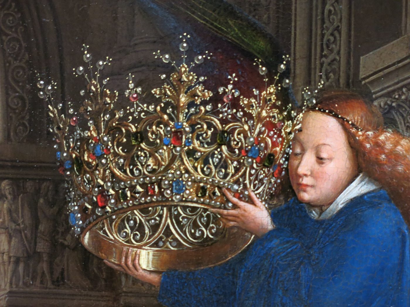 Painting of Chancellor Rolin kneeling in a fur-trimmed robe facing the Virgin Mary and infant Christ across a columned loggia, with a river city visible through arches behind