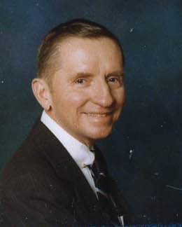 Head and shoulders photograph of Ross Perot in a dark suit and tie, with short cropped hair, looking slightly to the side