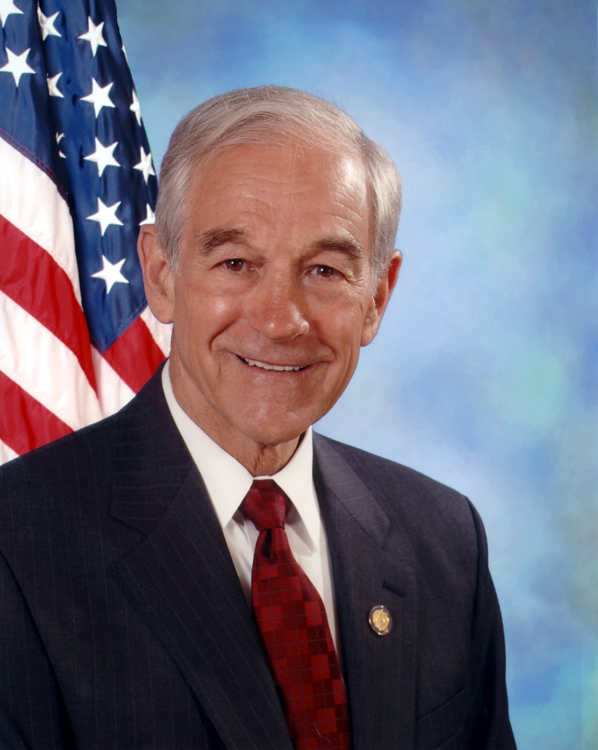 Official congressional portrait of Representative Ron Paul in a dark suit and red tie in front of an American flag