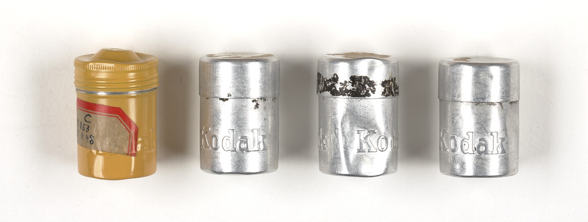 Three small round metal film canisters with paper labels, photographed side by side against a plain background