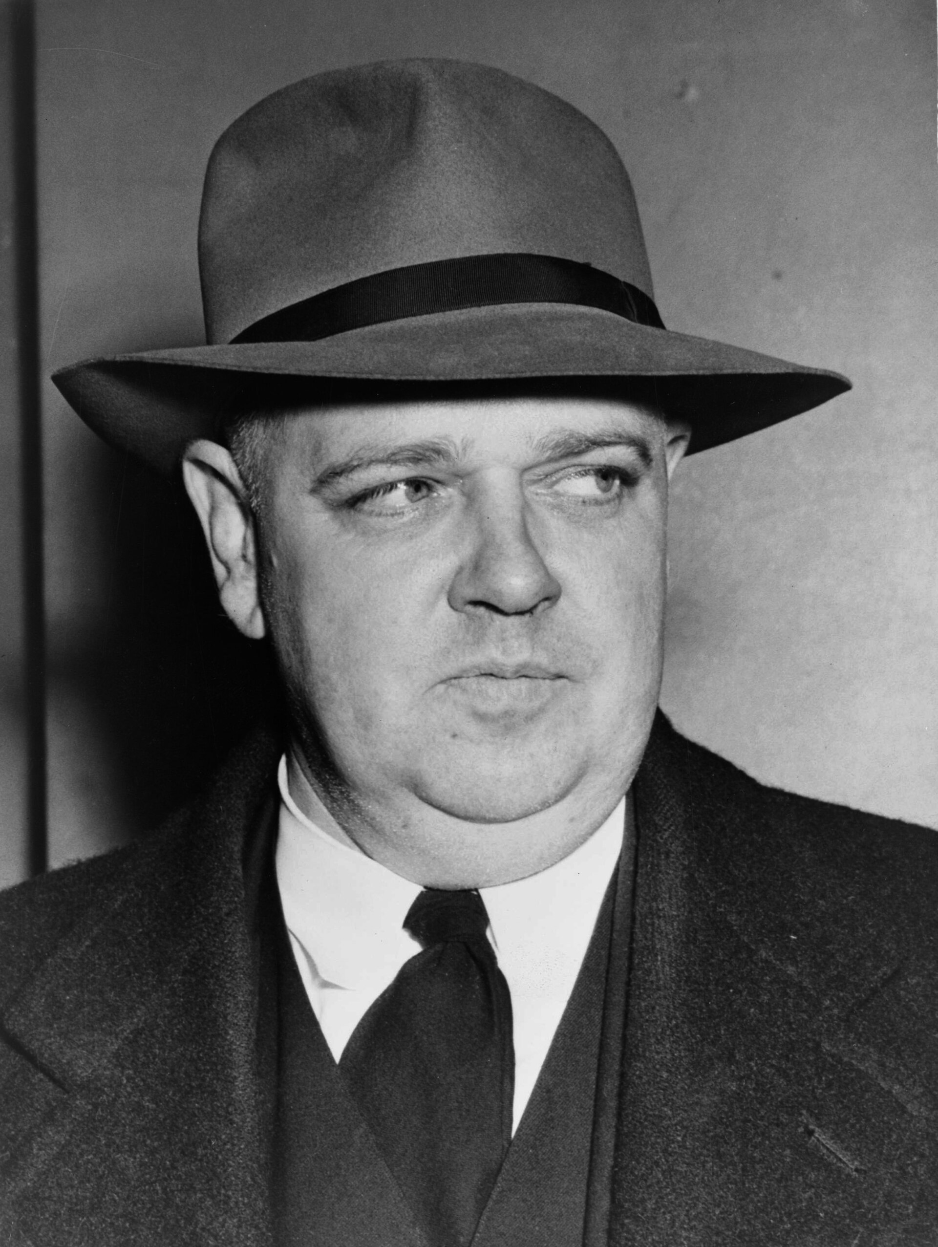 Black and white photograph of Whittaker Chambers, a heavy-set man with receding hair and a dark suit, seated and looking to one side