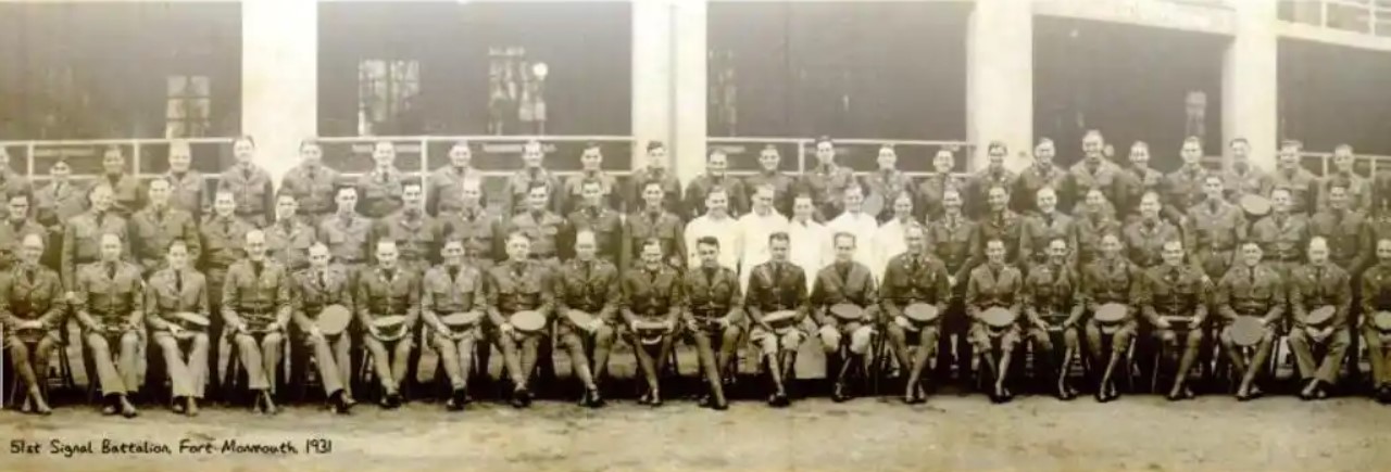 Panoramic group photograph of rows of uniformed soldiers, some seated and some standing, in front of a long building, with a handwritten caption reading 51st Signal Battalion, Fort Monmouth, 1931