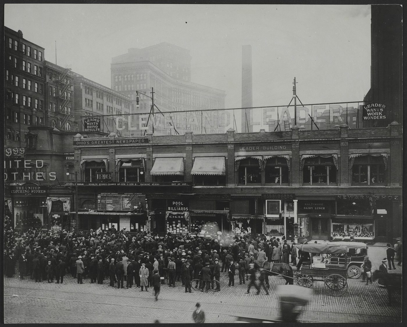 Crowd filling a city street to watch a bulletin board on a newspaper building