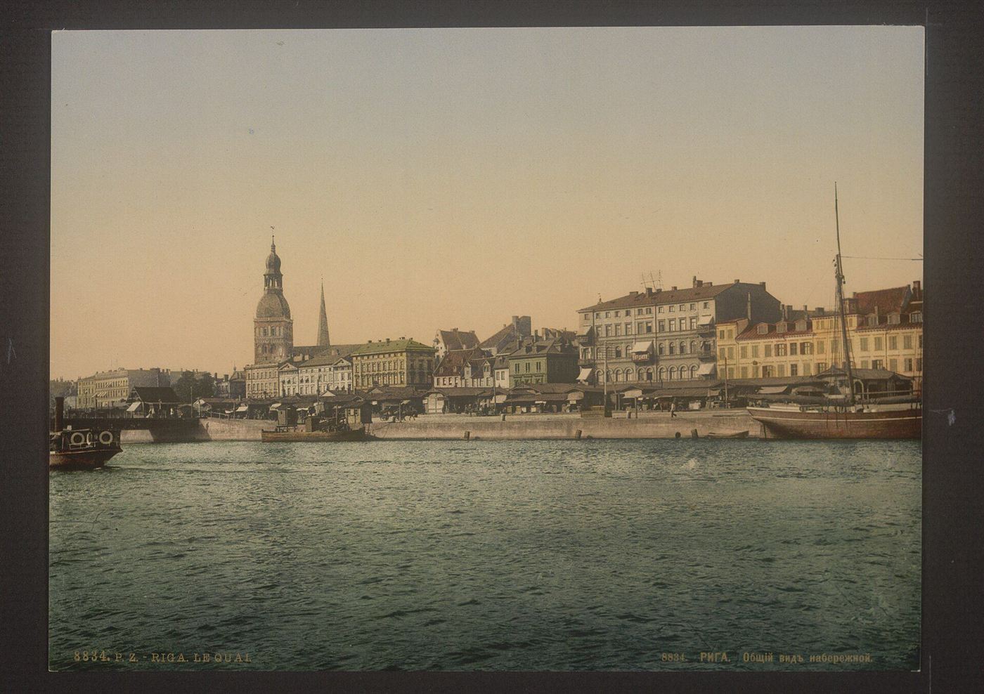 A color photochrom view of the quay at Riga in the 1890s, with ships moored along the river and church spires behind
